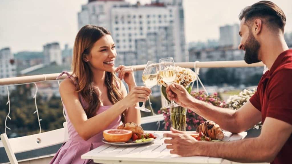 Couple eating and drinking wine with no phones, enjoying deep conversation.