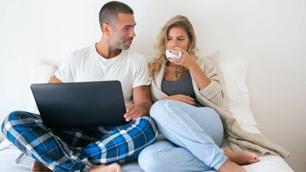 Woman looking disappointed while man works with late again.