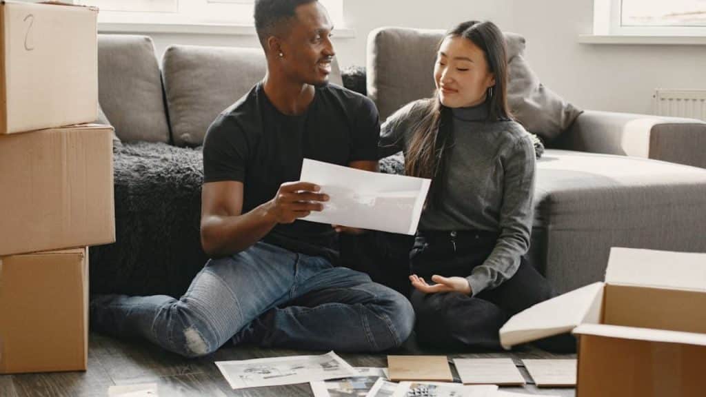 Couple making plans together with sheets of paper on the floor.