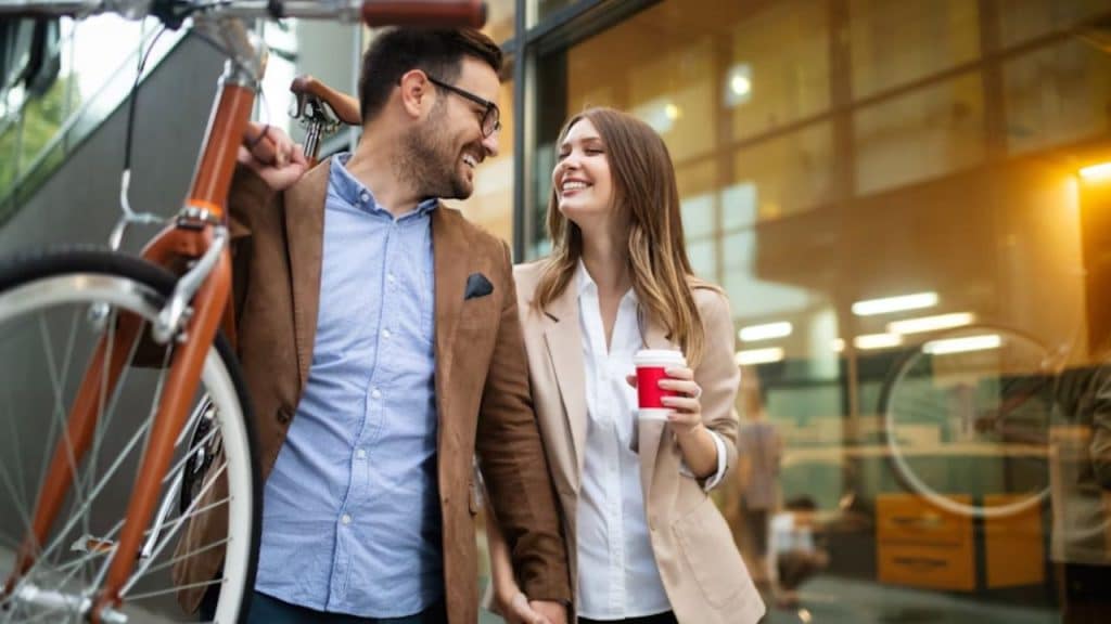 Man happily walking hand in hand with partner on the way to work.