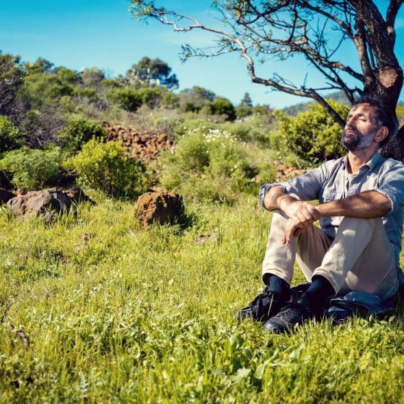 A man sitting peacefully on the grass.