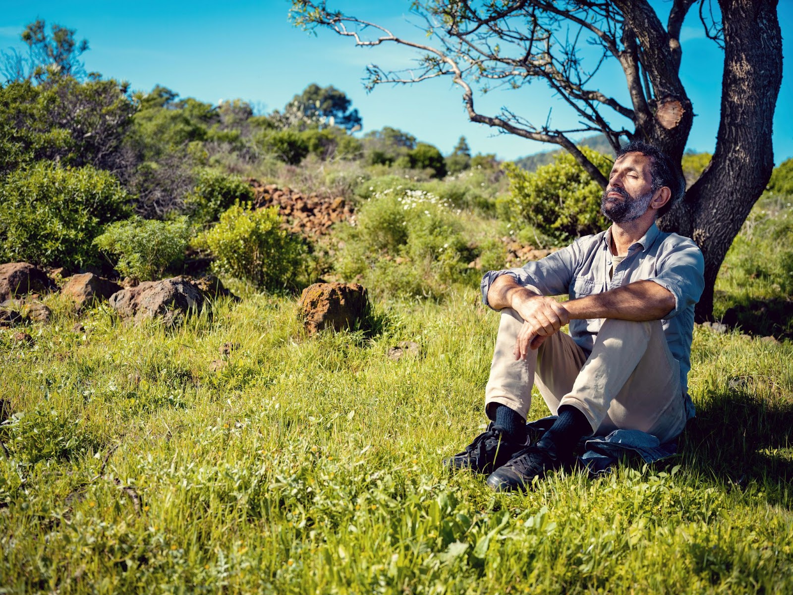 A man sitting peacefully on the grass.