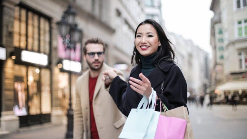 Woman holding shopping bags with a man looking concern from the side.