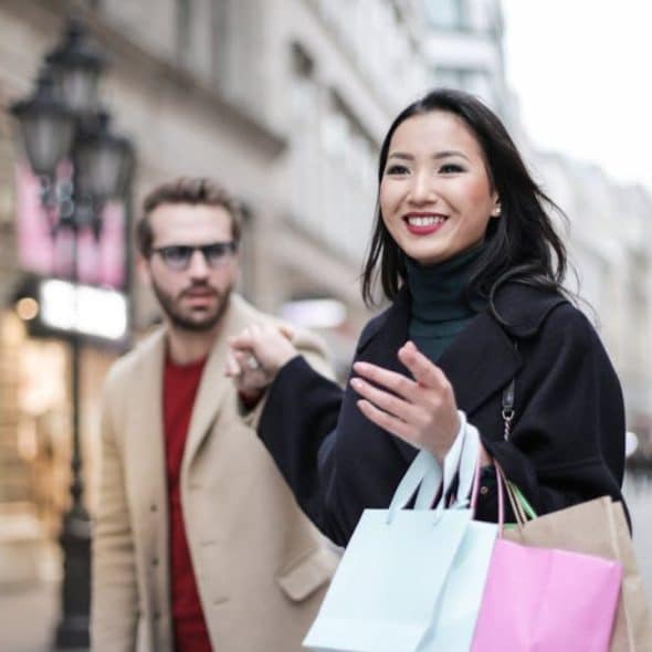 Woman holding shopping bags with a man looking concern from the side.