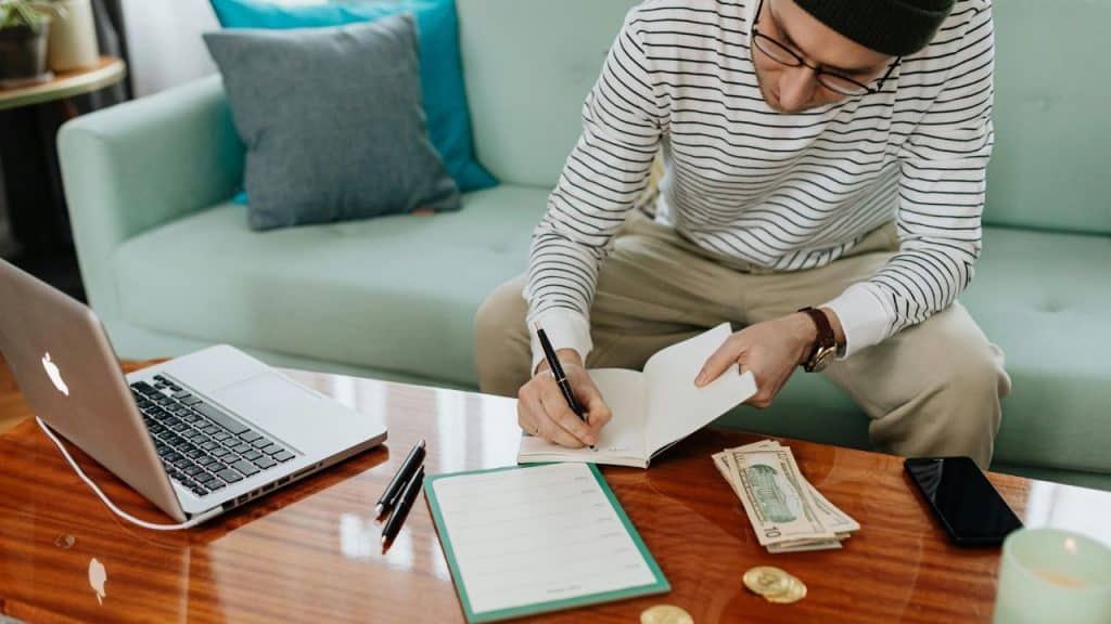 Man writing a personal finance plan in a notebook.