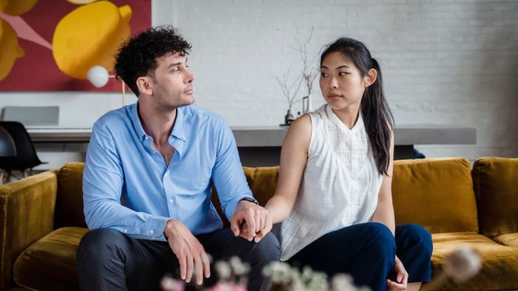 Couple seated on couch, having a peaceful and thoughtful conversation.