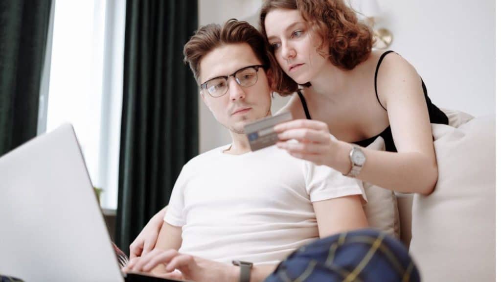 Couple smiling while reviewing spending together on a laptop.