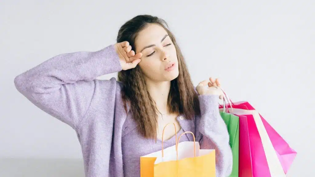 Woman holding shopping bags feeling stressed.
