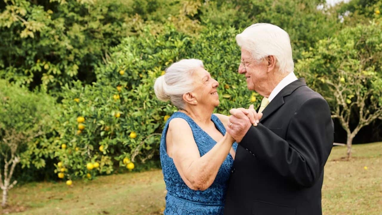 Older couple smiling while dancing in the park.