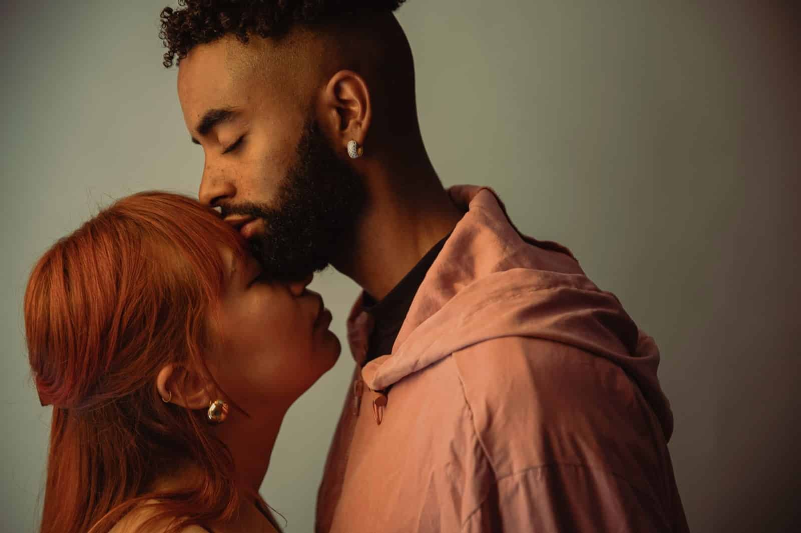 A man and kissing a woman’s forehead.