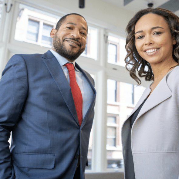 A man and a woman wearing business casual and smiling