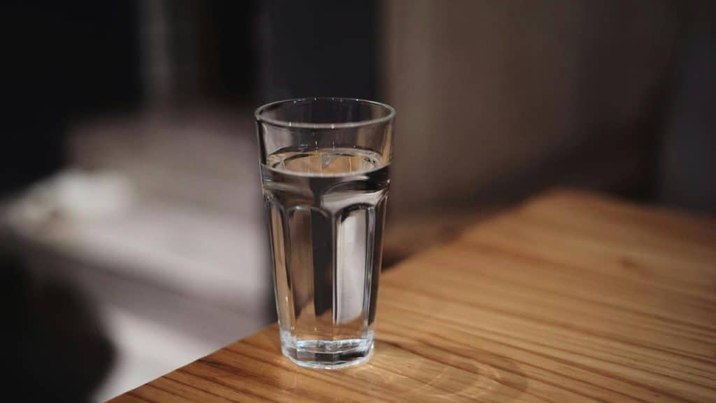 A glass of water on a wooden table.