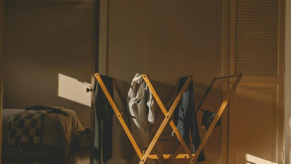 A wooden drying rack draped with clothes, bathed in warm sunlight.