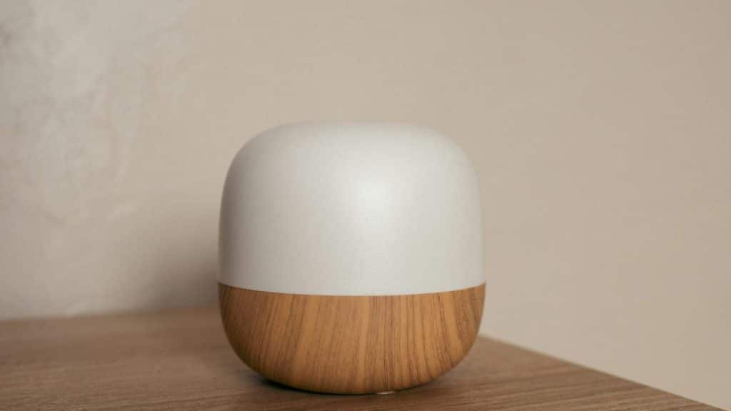 A white and wood tabletop diffuser sitting on a wooden surface.