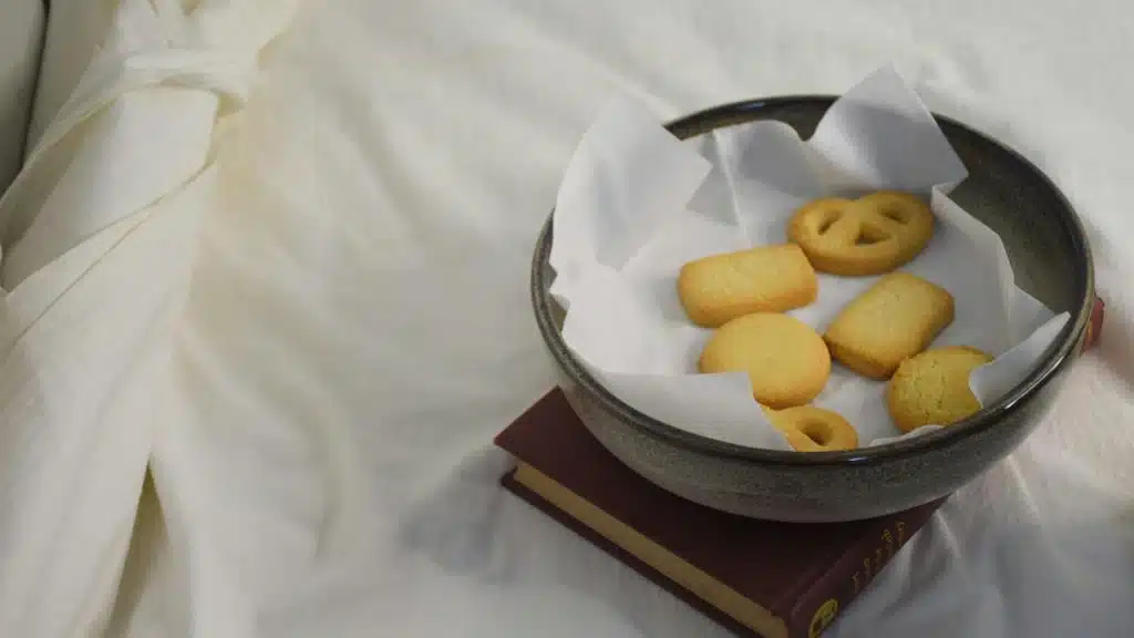 A bowl of assorted cookies on parchment paper atop a closed book.