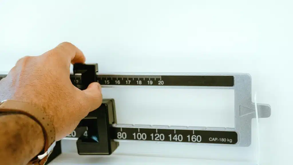 An image of a hand adjusting the weights on a mechanical medical scale.
