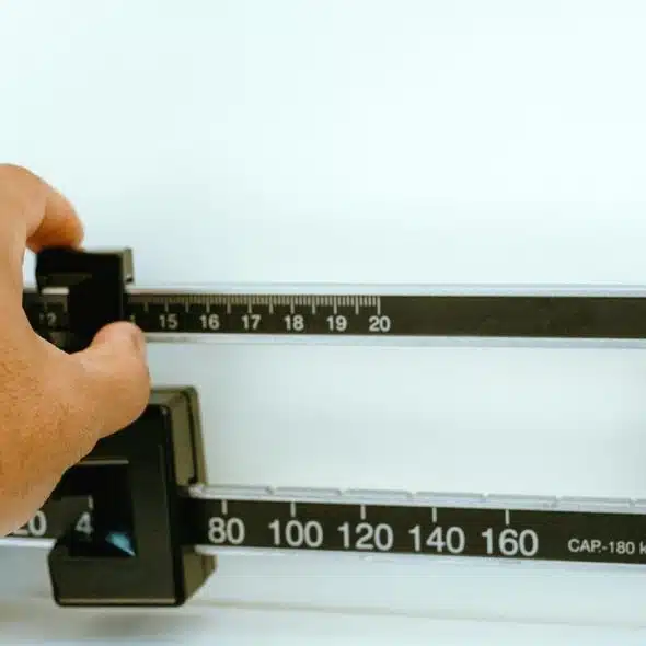 An image of a hand adjusting the weights on a mechanical medical scale.