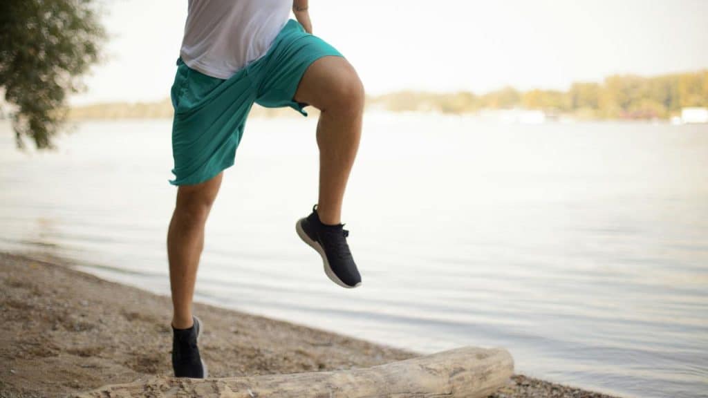 A man doing stationary running beside the lakeshore.