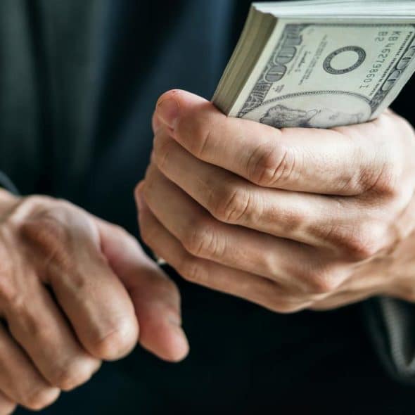 A person holding a thick stack of hundred-dollar bills.