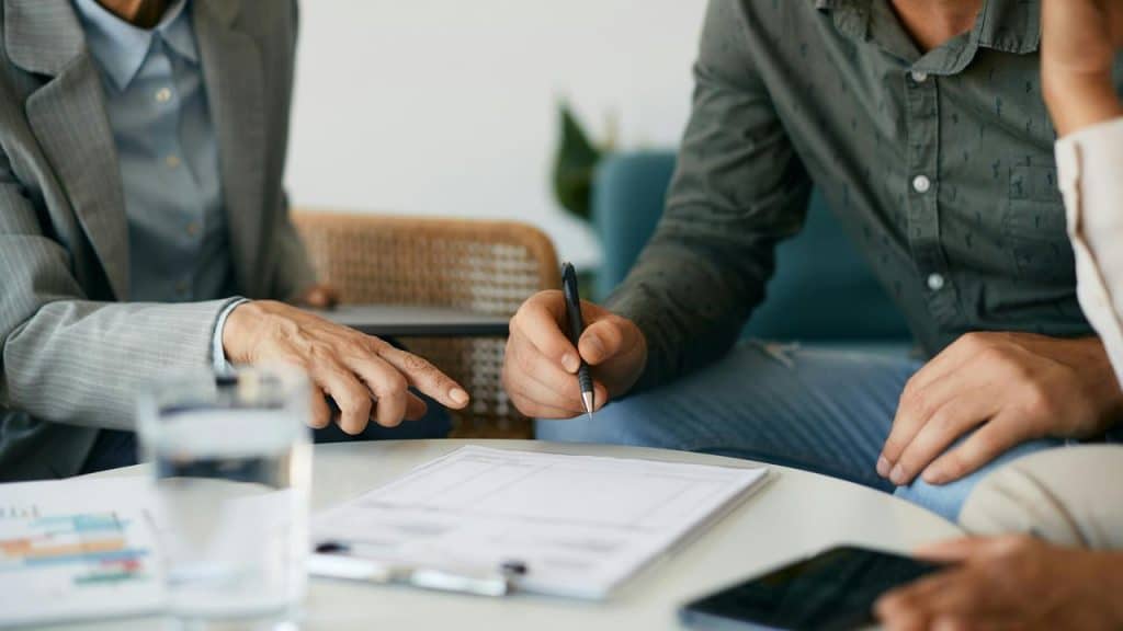 A business meeting with people discussing and signing a document.