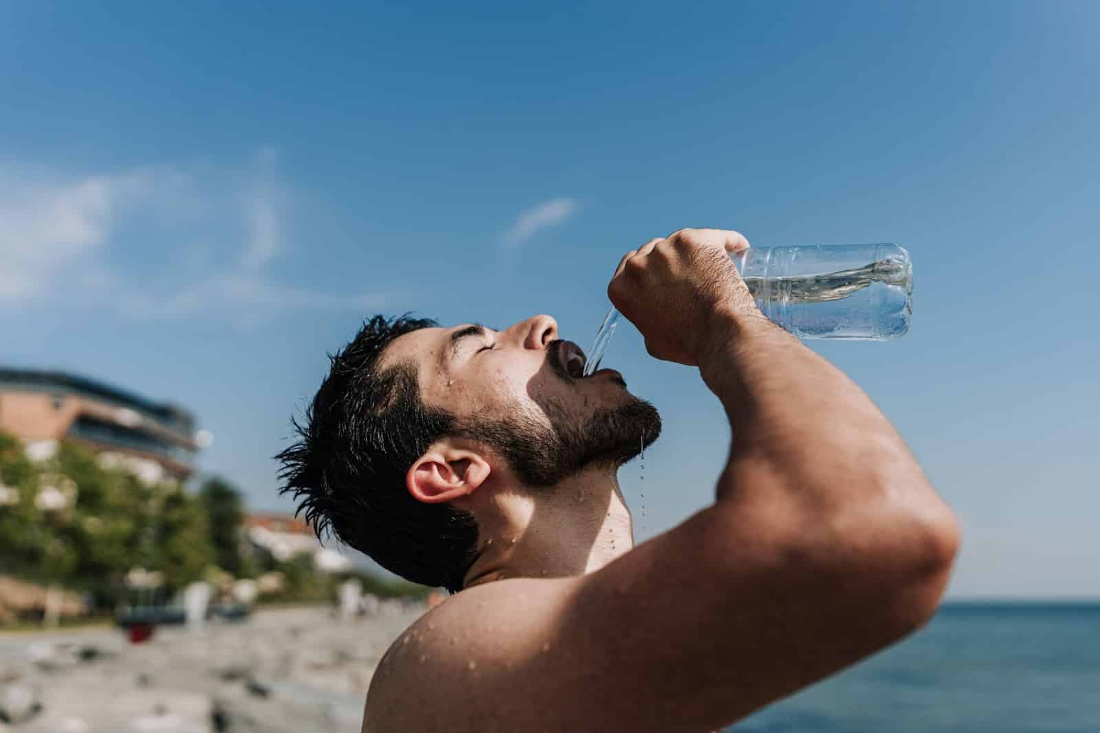 A man drinking a water from a water bottle.