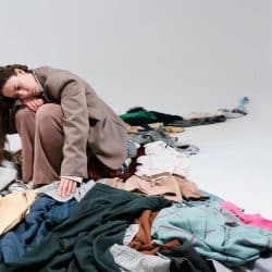 A woman looking sadly at a pile of clothes.