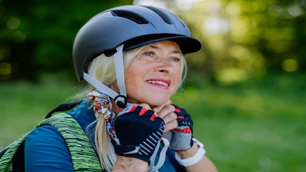 A woman putting on her helmet before biking.