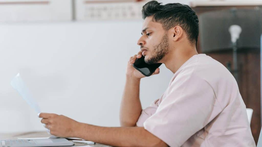 A man reading a document and talking on the phone.