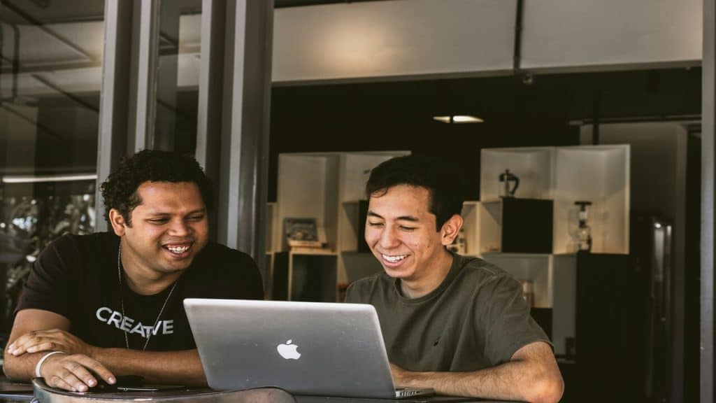 Two colleagues looking at a laptop while smiling.