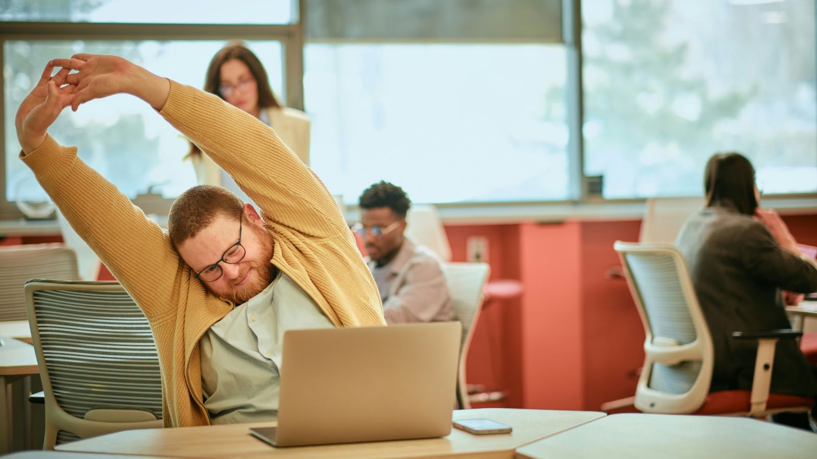 A man smiling while stretching at work.