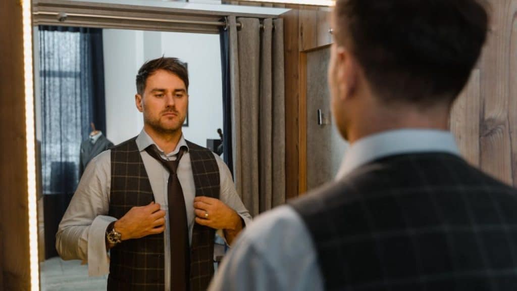 A man staring thoughtfully at his reflection while getting ready