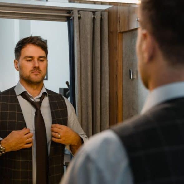 A man staring thoughtfully at his reflection while getting ready