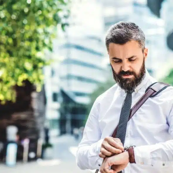Busy man in office attire looking at his watch and is heading to work