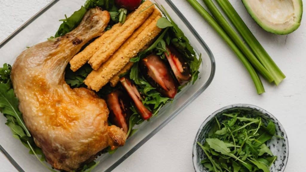 Meal prep container with grilled chicken and greens