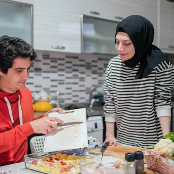 A man and a woman cooking together, blending culinary traditions in a cozy kitchen