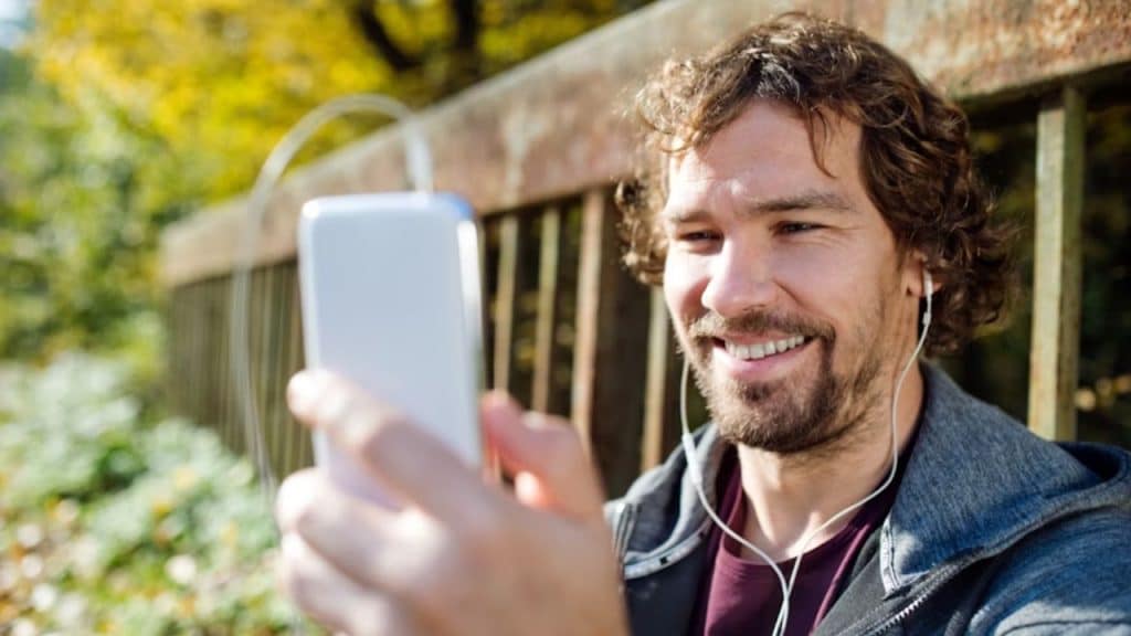 Man smiling while chatting on his phone outdoors.