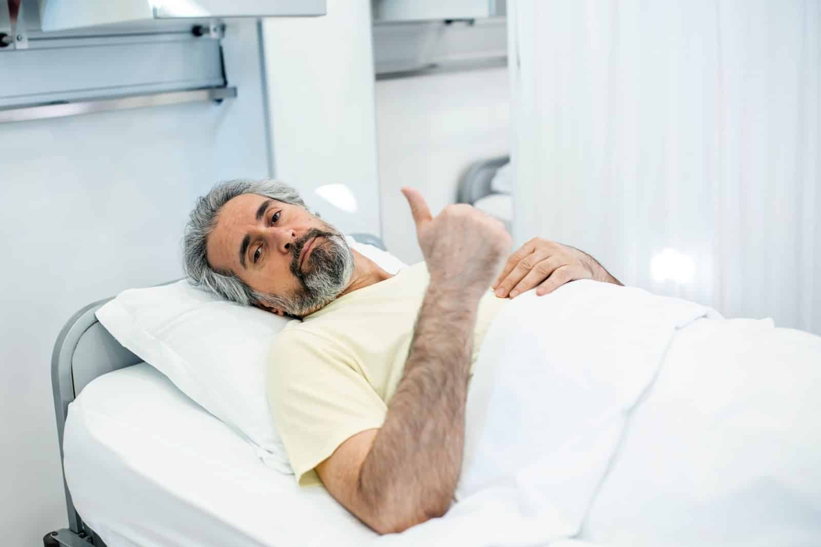 A man laying at the hospital bed.