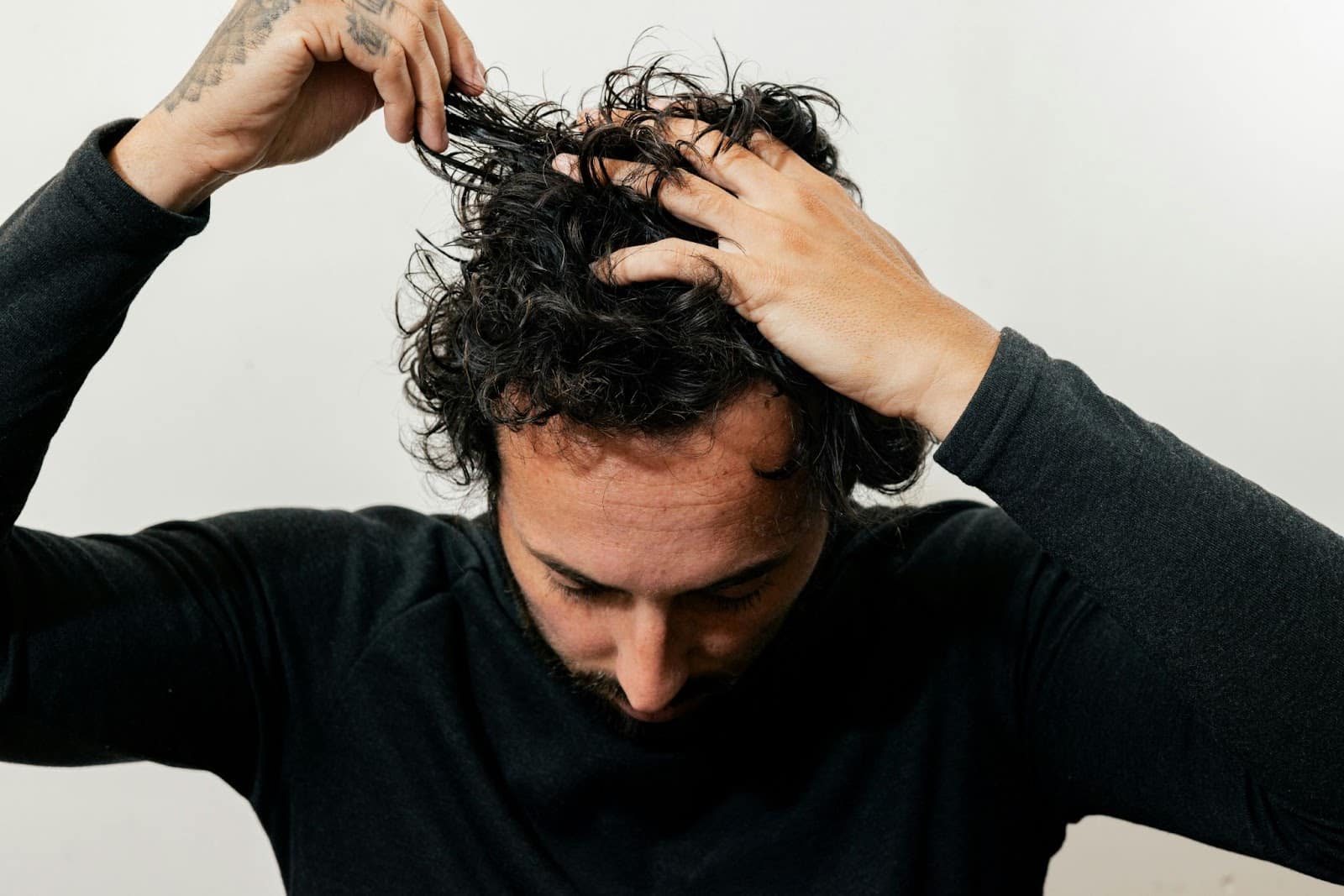 A picture of a man touching his hair.