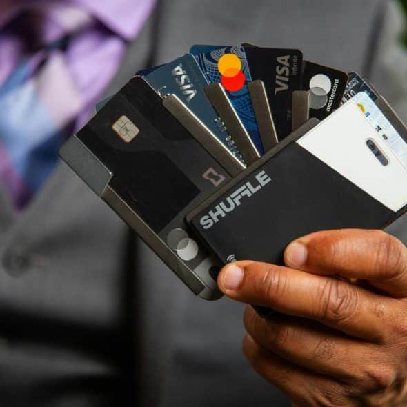 An individual in a suit holding a sleek cardholder fanned out with multiple credit and ID cards.