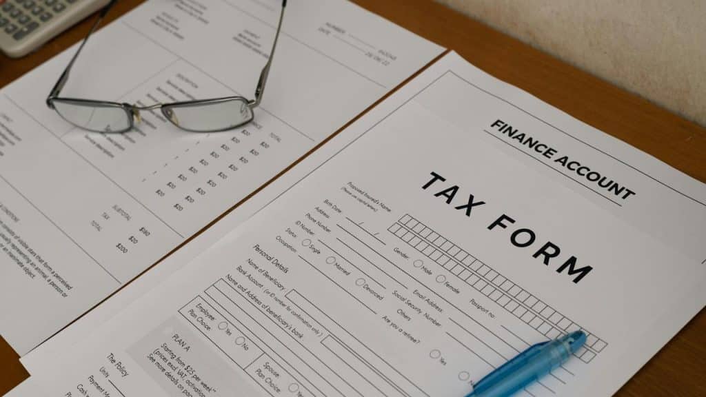 A tax form and financial documents with eyeglasses and a pen on a desk.