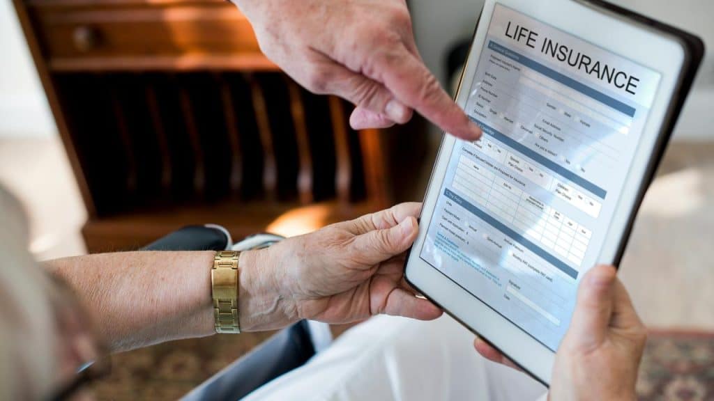 A tablet displaying a life insurance form as one person points and another holds it.