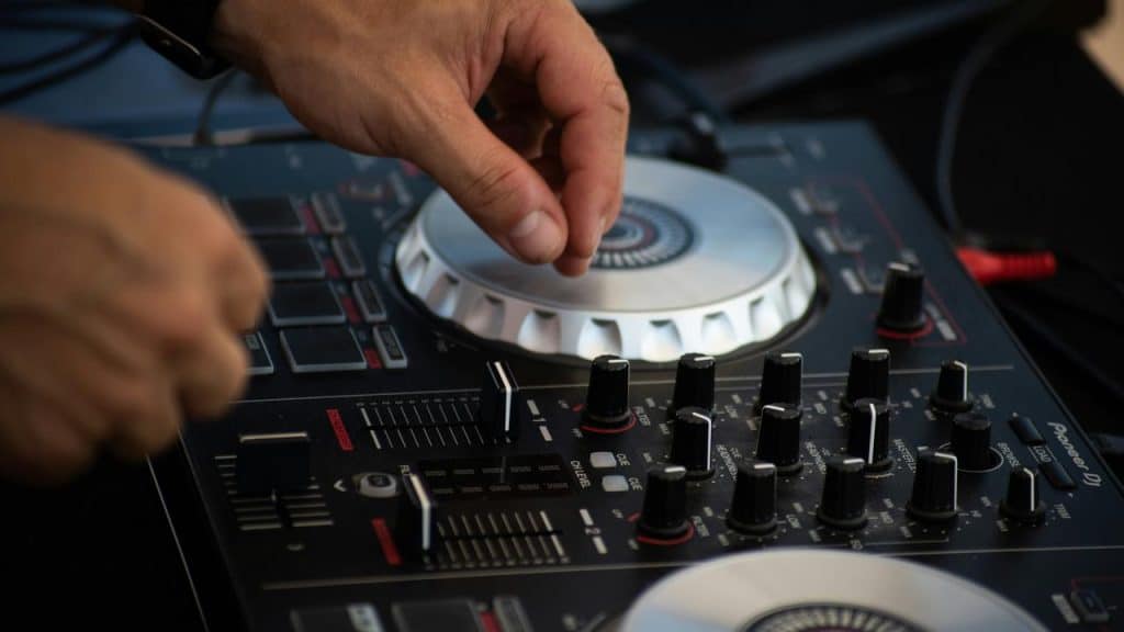 A hand adjusting knobs on a DJ mixer.