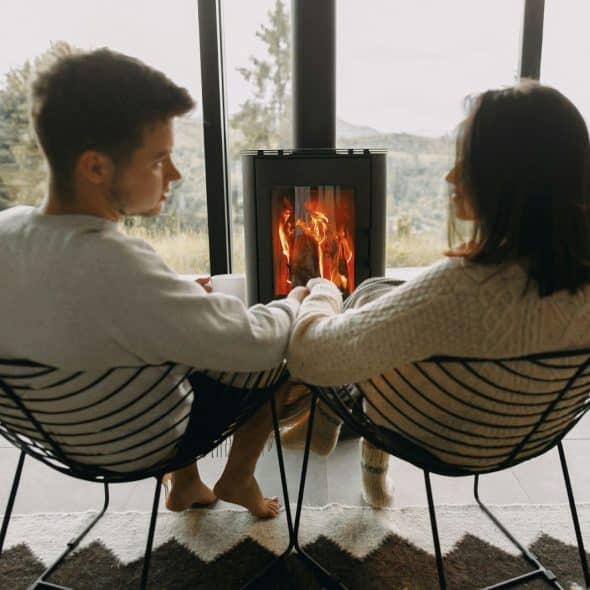 A man and woman sitting in front of the fireplace