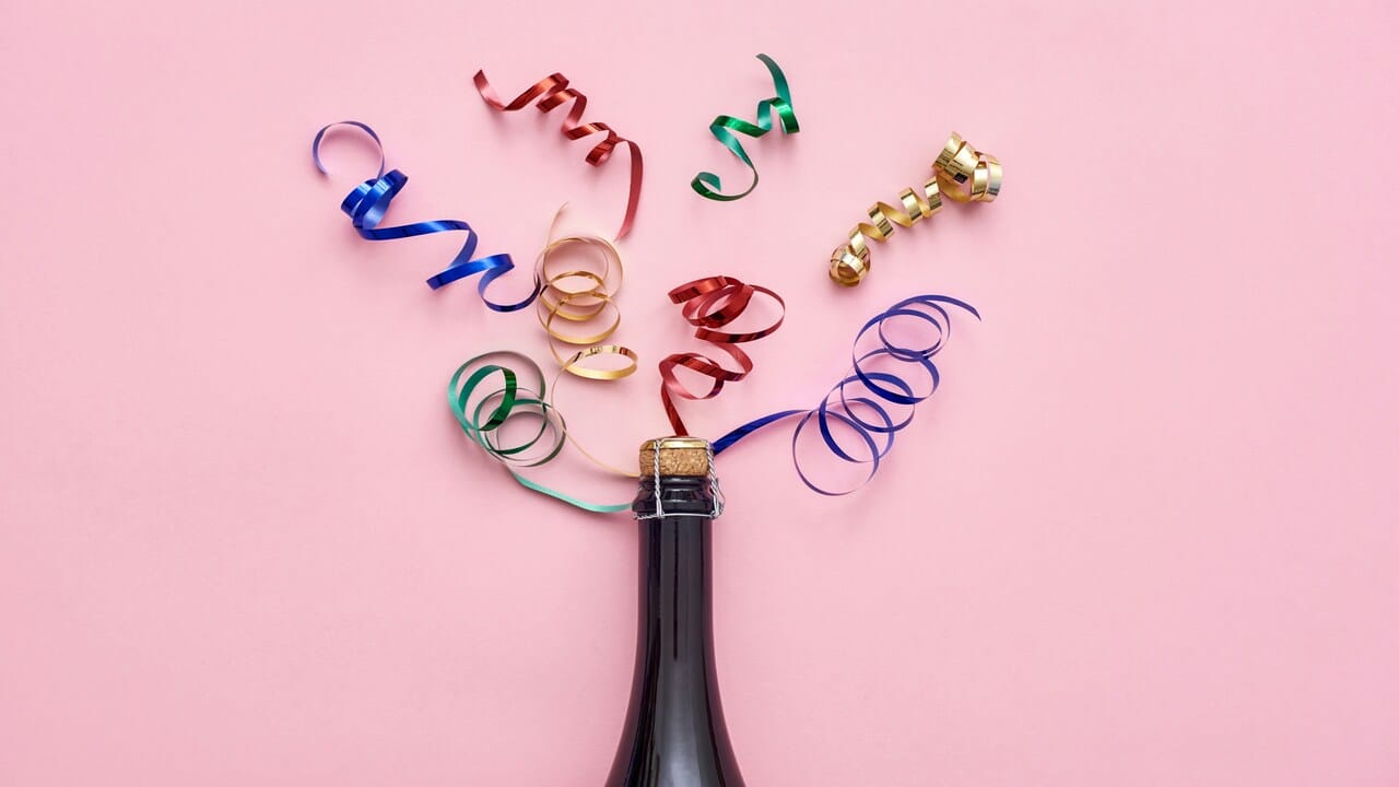 Shiny ribbons coming out of a champagne bottle.