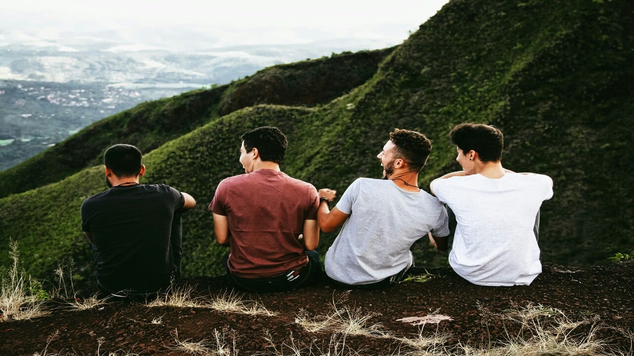 Four men laughing while looking at a mountain.