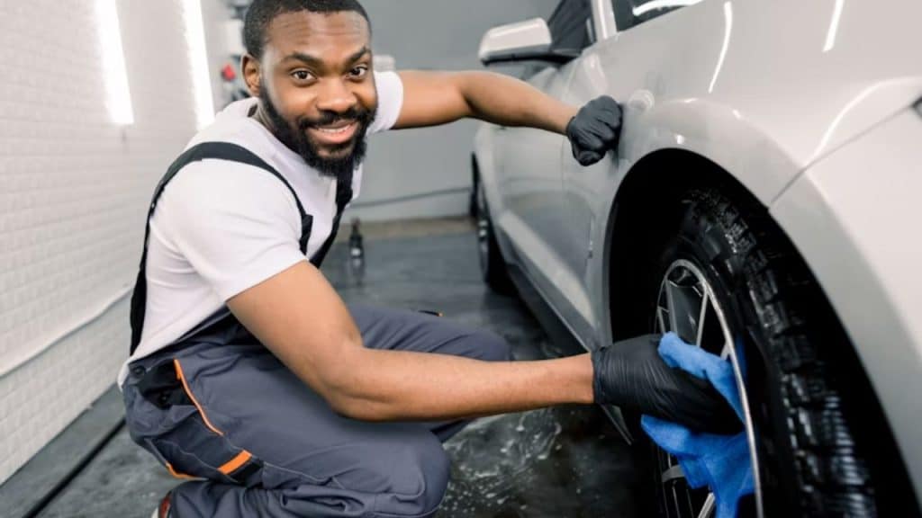A man polishing his car in a driveway