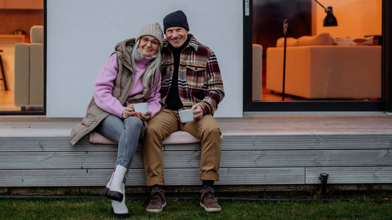 A senior couple sits facing away, looking out a large window.