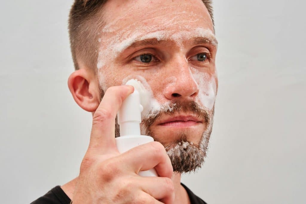A man washing his face with a facial cleanser.