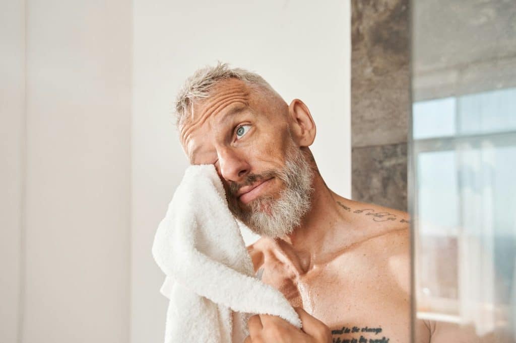 A man wiping his face with a towel.