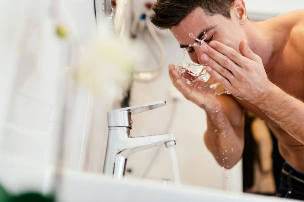 A man wetting his face.